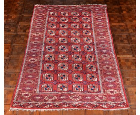 A Bokhara carpet, the madder field decorated with four rows of guls in tones of orange, cream and navy, approximately 298 x 1