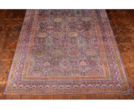 A Kirman carpet, the polychrome field decorated with multiple medallions and surrounded by floral and foliate motifs, the bor