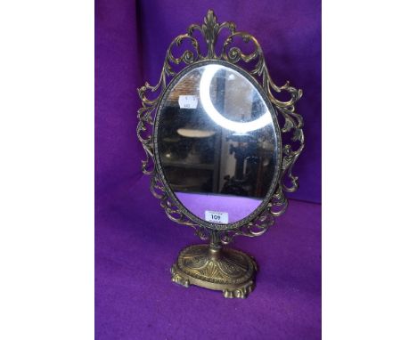A vintage brass bodied mirror having scroll work frame