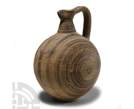 Iron Age, circa 900-700 B.C. With spherical body, conical neck and pinched trefoil mouth, gusseted strap handle; concentric p