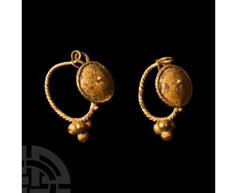Circa 1st-2nd century A.D. Comprising a matched pair of delicate earrings, each with a large circular boss with a central gra