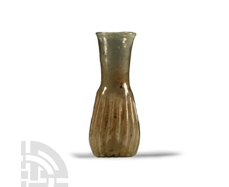 1st-3rd century A.D. A small mould-blown vessel with body formed from asymmetrical pleats, long neck, flared and rolled rim, 