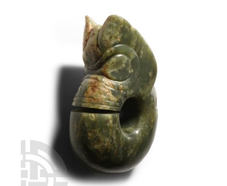 20th century A.D. Carved jade weight with grotesque face and penannular D-section body, pierced at the neck.  644 grams, 12.2
