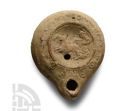 2nd century A.D. Squat lamp with broad discus displaying stamped scrolls and leaf-motifs, central low-relief biga with traces