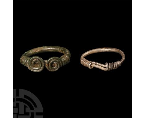 1st century B.C.-2nd century A.D. Pair of rings comprising: a bronze ring with overlapping terminals tapering into coiled dis