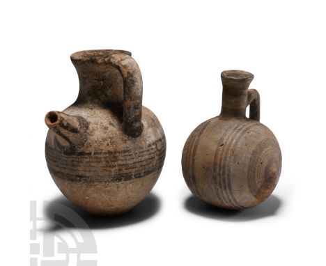 Early Iron Age, circa 950-850 B.C. Comprising: a spherical vessel with trumpet-shaped mouth and strap handle, painted concent