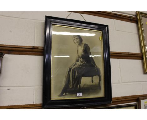 An ebonised framed black and white photographic print of a seated lady 