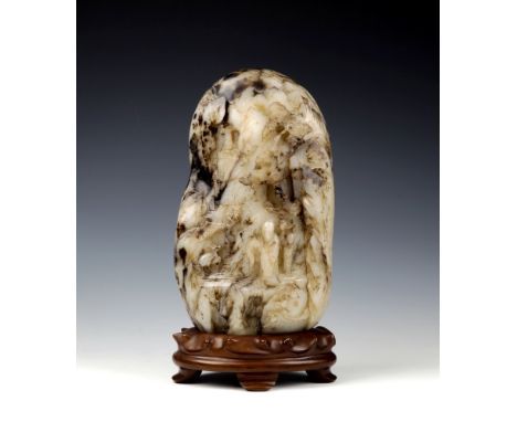 A large Chinese jade mountain carvingpale celadon and dark brown mottled jade, of irregular shape, carved to both side with a
