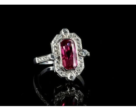 An 18ct white gold, ruby and diamond Art Deco style cluster ring, the 2.59ct cushion cut ruby within an octagonal border set 