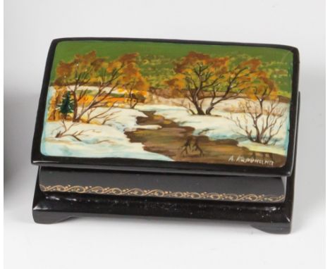 A 20th century Russian lacquer boxof rectangular form, the hinged cover decorated with a winter stream scene, with farm in th