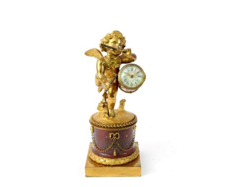 A French ormolu and variegated red marble novelty mantel time piece, 19 th century, cast as a winged cherub playing a drum co