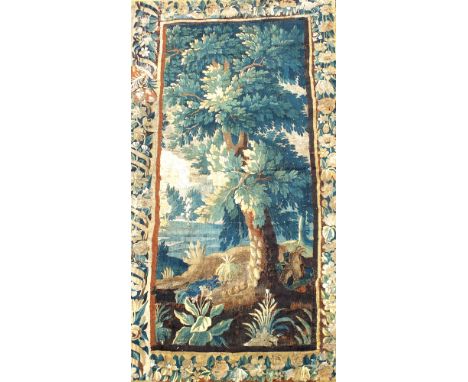 A French verdure tapestry, late 17th century, showing a leafy tree in a landscape within broad foliate borders, later lined 2