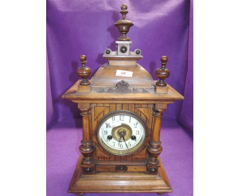 A vintage treen mantle clock with ornate work, enamel face and chime