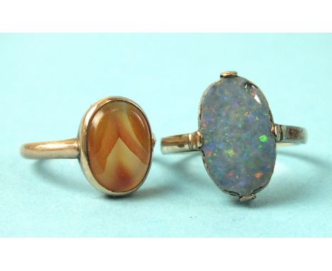 A small unmarked gold ring collet-set an agate, size K, 2.4g and a 15ct gold ring claw-set a black opal doublet, (a/f), size 