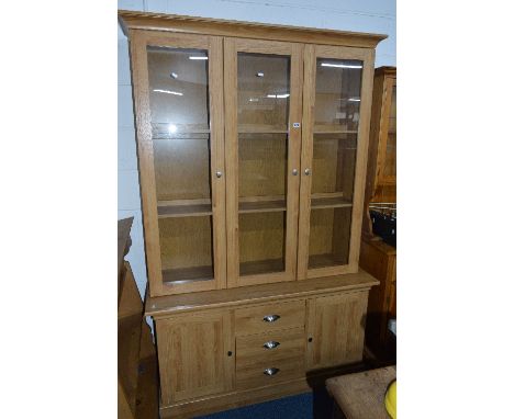 A LIGHT OAK VENEER GLAZED THREE DOOR BOOKCASE, above three central drawers, approximate size width 129cm x height 201cm x dep