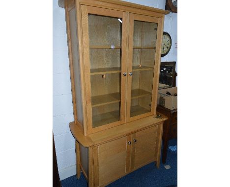 A MODERN LIGHT OAK GLAZED TWO DOOR BOOKCASE, above a cupboard base, approximate size width 110cm x 194cm x depth 50cm (sd)