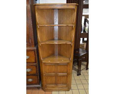 AN ERCOL ASH OPEN CORNER CABINET, revealing three tier shelf above single panelled cupboard