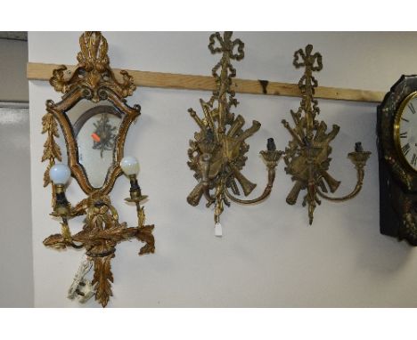 A PAIR OF GILTWOOD WALL LIGHTS, with ribbon, musical instrument and foliate scroll backs, supporting twin branch candle holde