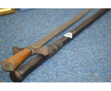 A BLACK COLOURED WOODEN WALKING CANE, possibly African in origin, carved decoration below grip, metal end cap, also a crude, 