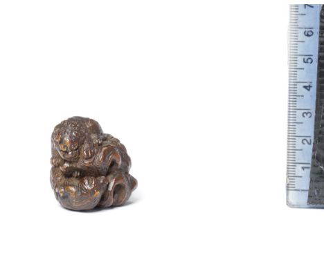 A wood netsuke of a shishi (Chinese mythological lion dog) and cubBy Kokei, early 19th centuryThe adult shishi standing on a 