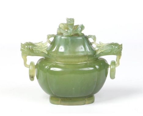 A Chinese carved jade censor and cover of ovoid quatrefoil form with black inclusions. The cover is surmounted with a coiled 