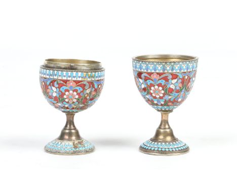 A pair of Russian enamelled silver pedestal egg cups. Red ground and decorated in pale blue, purple white and green with flow