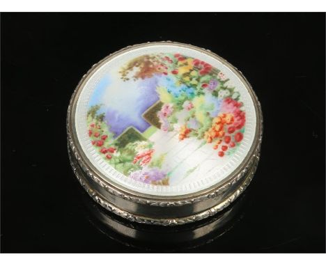 An imported silver pill box with hinged cover enamelled with a garden landscape. Import hallmarks for London 1927, 5.25cm dia