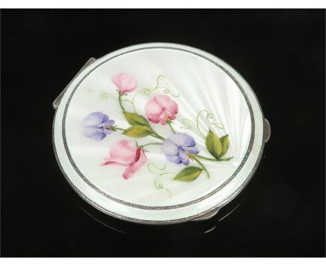A large silver powder compact. With white guilloche enamel top decorated with sweet pea. Assayed Birmingham 1952, 10cm diamet