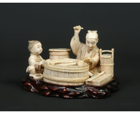 A Japanese Meiji period carved ivory okimono group on fitted hardwood plinth. Formed as a seated cooper crafting a barrel wit