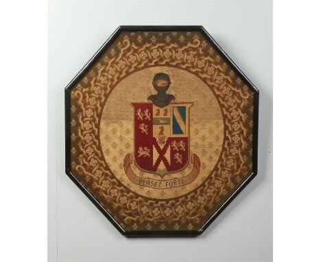 A 19th century woolwork armorial panel of octagonal form and in ebonized frame. Depicting a coat of arms and with Latin motto