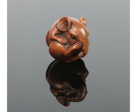 A Japanese carved fruitwood netsuke. Formed as a rat curled into a ball, with glass inset eyes and incised signature, 3.75cm.