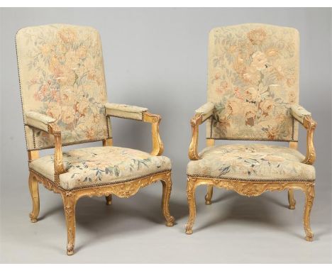 A pair of early 20th century carved giltwood open armchairs. With overstuffed tapestry upholstery embroidered with flowers an