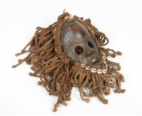 A West African Ivory Coast carved hardwood tribal Dan Zakpei mask with ropework border decorated with cowrie shells, 28cm. Pr