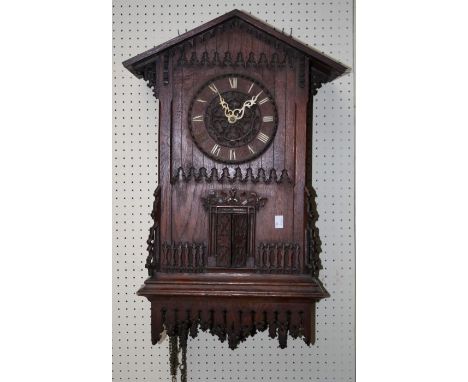 An early 20th century Black Forest Trumpeter wall clock, the architectural oak case with a hinged door revealing figure with 