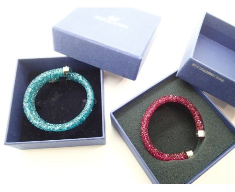 Two Swarovski bangles one in ruby coloured crystals with stainless steel terminals and the second longer bangle in aquamarine