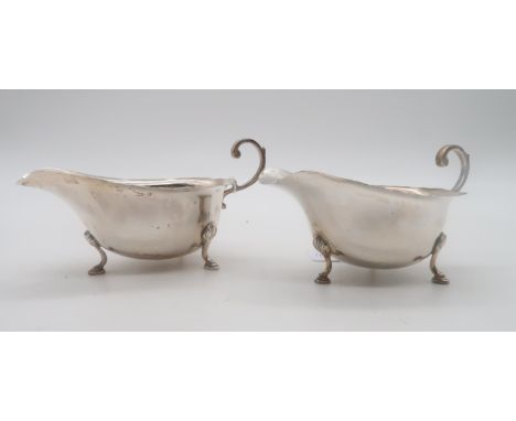 A pair of silver sauce boats, by L &amp; R, Birmingham 1932, in the George III style, with a flying scroll handle, on three s