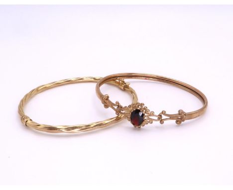 A 9ct gold garnet set bangle, together with a 9ct twist pattern bangle, weight together 9.8gms Condition Report:Available upo