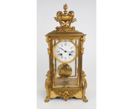 A French gilded brass and glass timepiece, of tall rectangular form, the top with flaming urn and torch finial, with acanthus