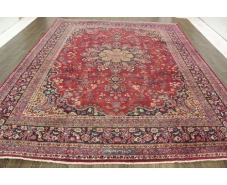 A North West Persian Woollen Carpet, with a central medallion upon an allover design within a red, blue and cream ground with