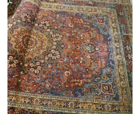 A North West Persian Woollen Carpet, with a central medallion within an all-over design upon a red and pale blue ground withi