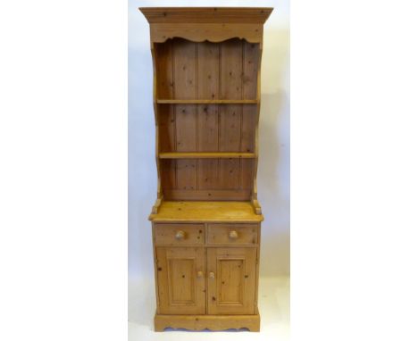 A Pine Narrow Dresser with a boarded shelf back above two drawers and two panel doors raised upon a plinth, 66 cms wide