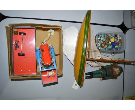 A West-German tinplate tractor and trailer, boxed; a small pond yacht; a Nutcracker figure; and a quantity of marbles.