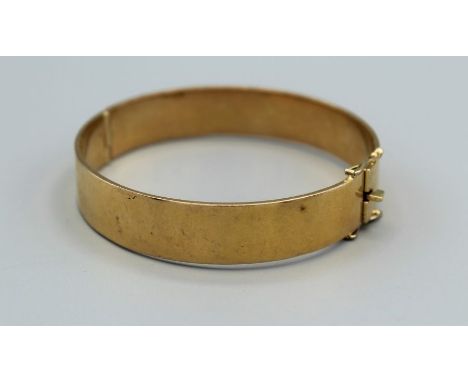 A substantial yellow metal hinged bangle, with a box clasp and double safety latches, gross weight approximately 68.4gm, alon
