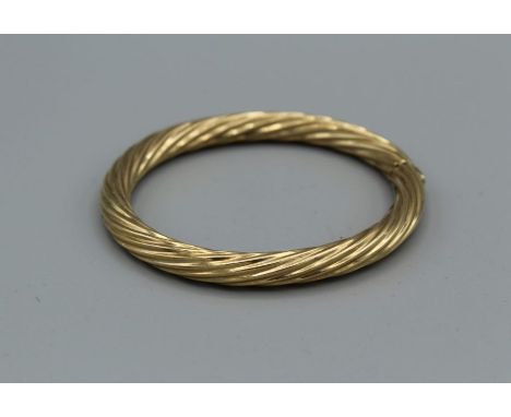 A hinged 9ct gold bangle in twisted form. Hinge and clasp in good condition, gross weight approximately 21.5gm