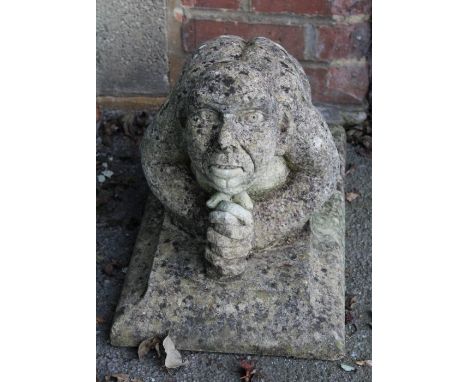 A reconstituted stone model of a kneeling goblin type creature, on rectangular plinth, 39 x 55 x 32cm