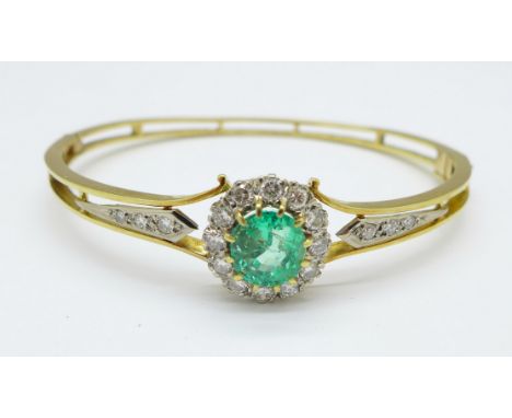 An emerald and diamond set bangle, set with eighteen diamonds, the emerald approximately 9mm x 7mm