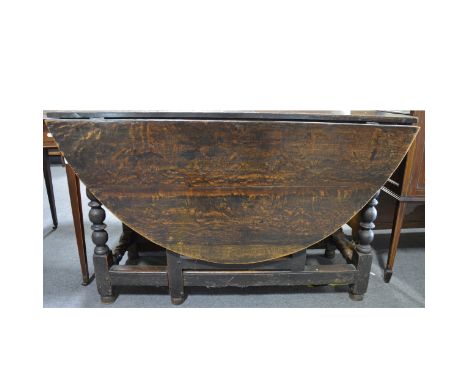 An old oak gateleg table, oval top, two leaves, frieze drawer, bobbin-turned base, the top 128cm x 158cm, height 74cm.