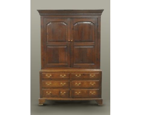 An 18th century panelled oak livery cupboard, with moulded and dentil cornice, fitted sixteen pegs enclosed by a pair of fiel