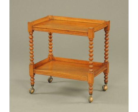 A 19th century mahogany two tier tea trolley, of traditional rectangular form, with rosette capped bobbin turned uprights rai