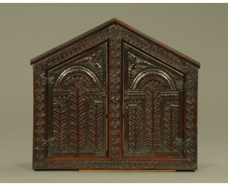 A 17th/18th century carved and panelled alms cupboard, with apex top, decorated throughout with guilloche, leaf and lunette c